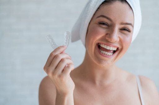 A woman holding her invisible aligners. 