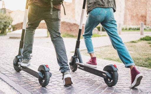 A couple riding e-scooters outdoors.