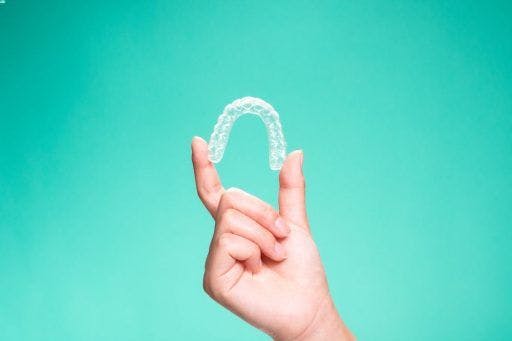 A hand holding ClearCorrect aligners. 