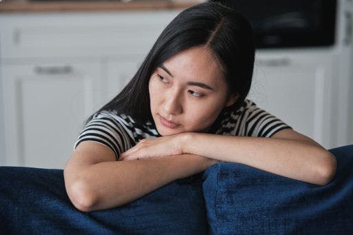 A woman resting her head on pillows and contemplating.