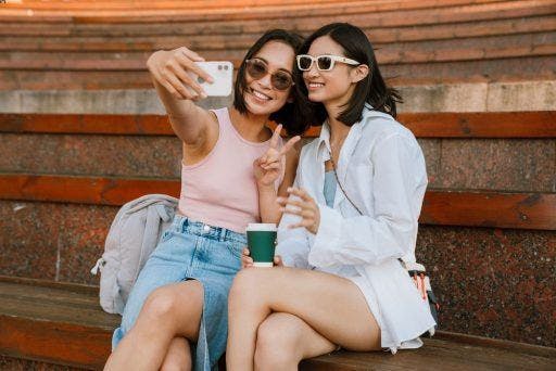 Two women smiling confidently while talking a selfie.