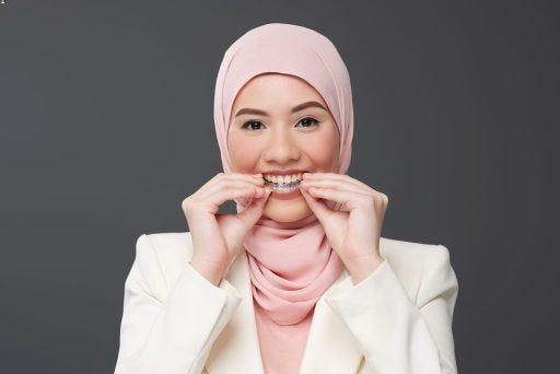 A woman putting on her invisible aligners.