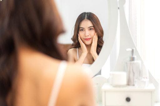 A woman checking her skin in the mirror. 