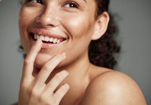 A woman smiling with sugar scrub on her lips.