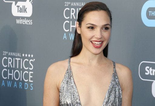 Gal Gadot smiling in a glittery silver dress during an awards ceremony.