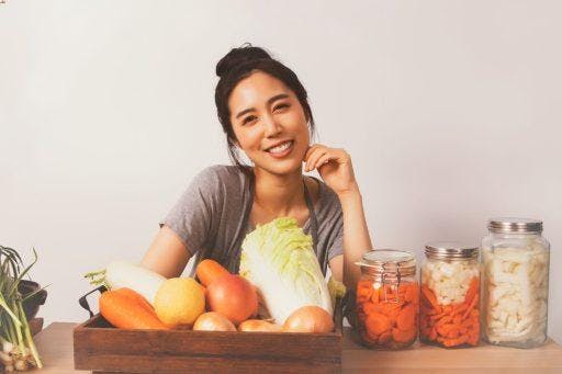 Woman smiling with a wooden crate of vegetables.