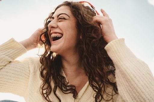Happy woman with braces wearing wireless headphones. 