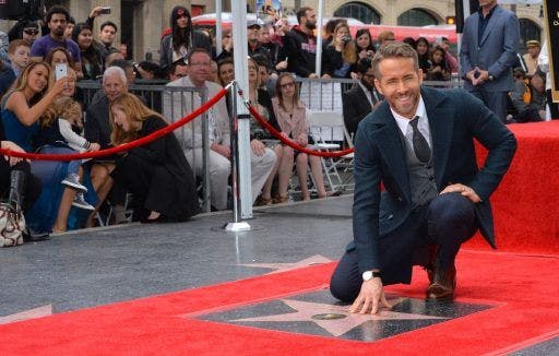 Ryan Reynolds in a suit smiling at a red-carpet event.