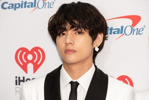 V in a white suit against a white event background.