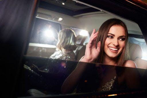 Smiling woman waving from inside a car.