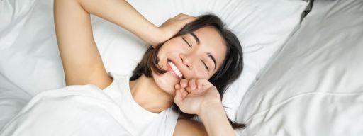 Smiling woman in white bed.