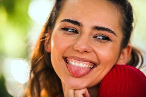 Close-up of a woman smiling and sticking her tongue out.