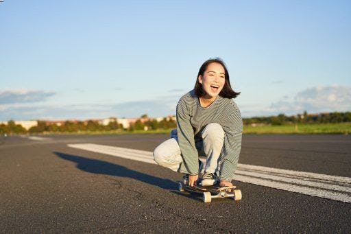 A happy woman riding a skateboard.