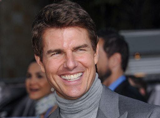 Tom Cruise in a grey turtleneck shirt smiling.