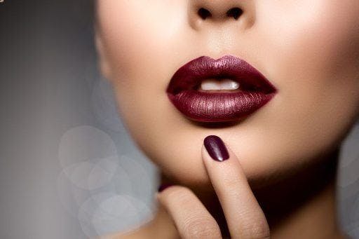 Close-up of a woman’s lips wearing a dark plum lipstick. 
