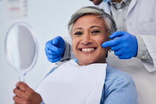 Woman smiling with a dentist behind her. 