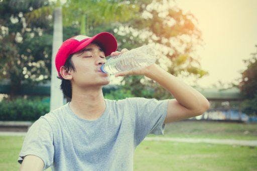 Teen drinking water from a bottle after exercising.
